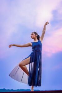 family photographer in rochester ny captures senior portraits for high school senior dancing in the sunset