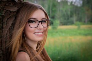 family photographer in rochester ny captures senior portraits for high school senior leaning against a tree at Tinker Park