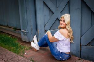 family photographer in rochester ny captures senior portraits for high school senior leaning against a gate at the Eastman Museum