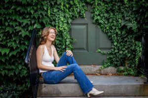 family photographer in rochester ny captures senior portraits for high school senior laughing on the steps at the Eastman Museum