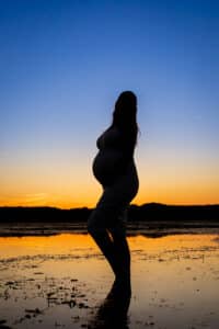 maternity photographer in rochester ny captures silhouette of pregnant mom in the water at mendon ponds