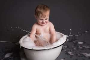 baby photographer in rochester ny captures baby splashing in a bubble bath