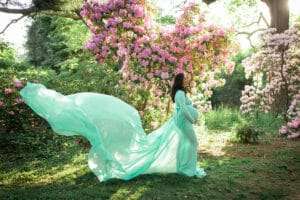 maternity photographer in rochester ny captures pregnant mom in a flowing gown in the flowers