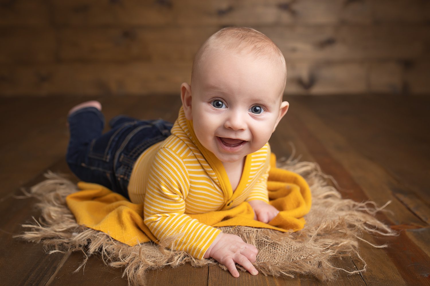 baby photographer in rochester ny captures 4 month old baby doing tummy time on rustic wood backdrop