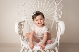 baby photographer in rochester ny captures baby girl in a wicker princess chair