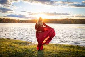 maternity photographer in rochester ny captures expectant mom with the sun setting behind her
