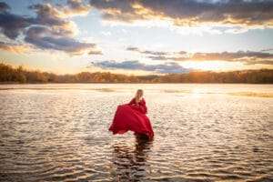 maternity photographer in rochester ny captures expectant mom in the water at sunset
