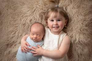 newborn photographer in rochester ny captures baby boy in big sister's arms