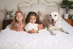 newborn photographer in rochester ny captures baby boy with big sisters and family dog