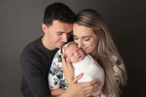 newborn photographer in rochester ny captures new mom and dad snuggling their baby girl