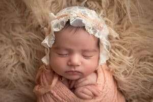 newborn photographer in rochester ny captures newborn baby girl asleep in a lace bonnet