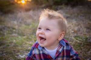 family photographer in rochester ny captures baby boy smiling in the sunshine