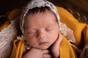 newborn photographer in rochester ny captures newborn baby girl sleeping in a lace bonnet