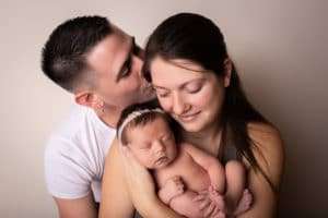 newborn photographer in rochester ny captures newborn baby girl sleeping in mom and dad's arms