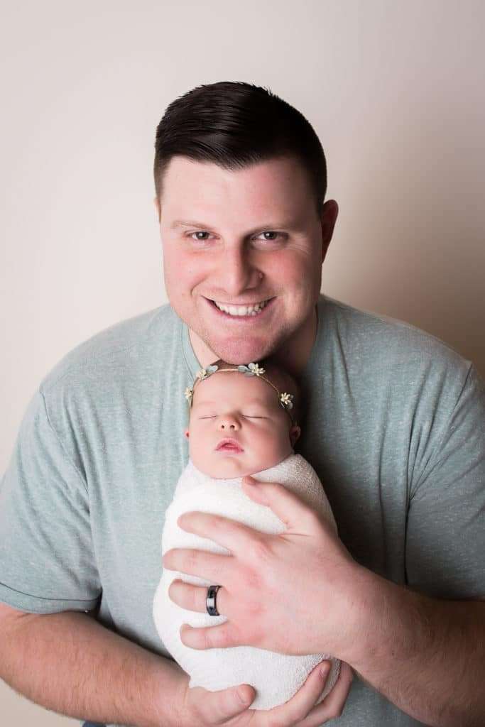 newborn photographer in rochester ny captures newborn baby girl sleeping in dads arms