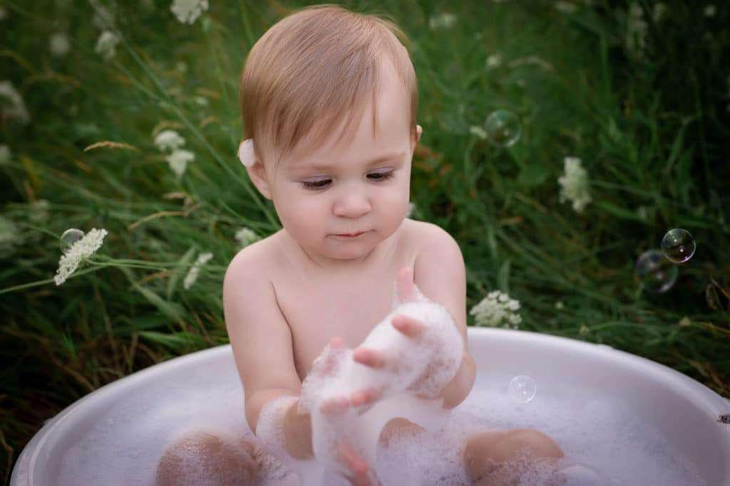baby photographer in rochester ny captures baby girls first birthday portraits with cake smash and bubble bath in Tinker Park