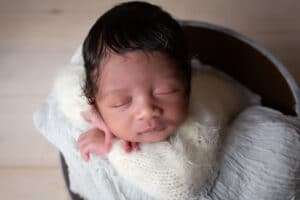 newborn photographer in rochester ny captures newborn baby boy sleeping i n a bucket