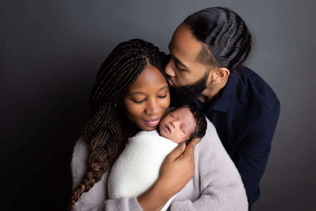 newborn photographer in rochester ny captures newborn baby boy sleeping in parents arms