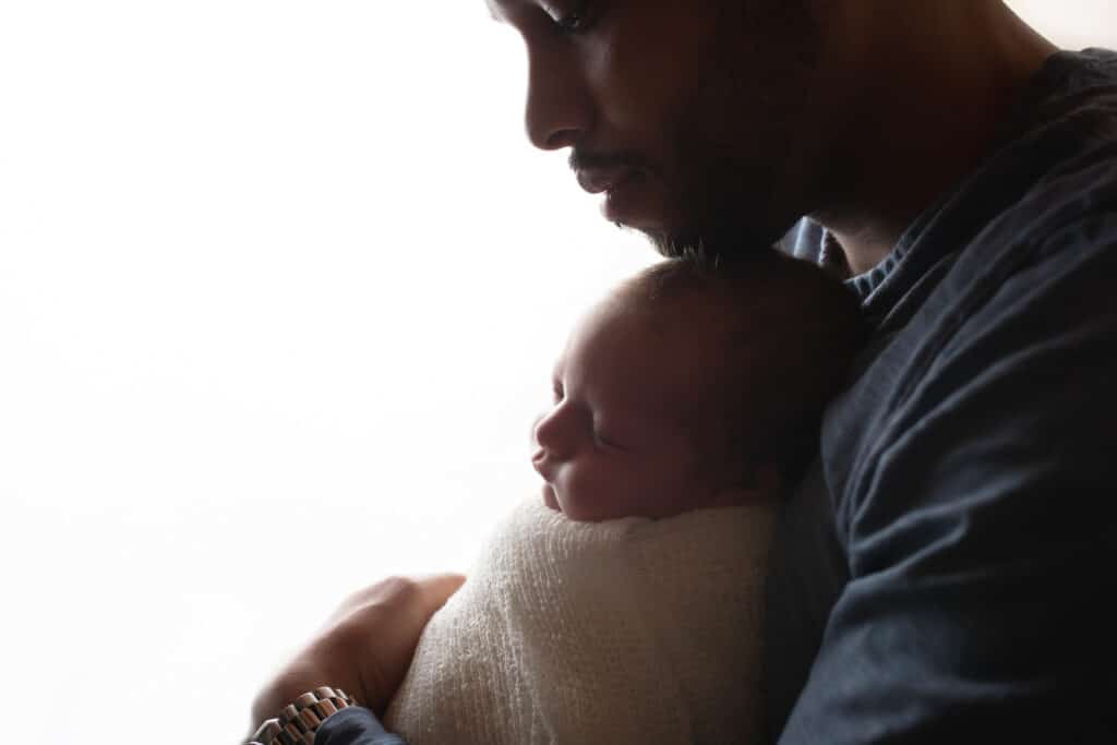 newborn photographer in rochester ny captures newborn baby boy sleeping in his dad's arms