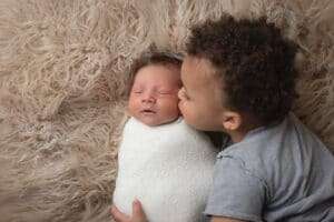 newborn photographer in rochester ny captures newborn baby boy getting kisses from his big brother