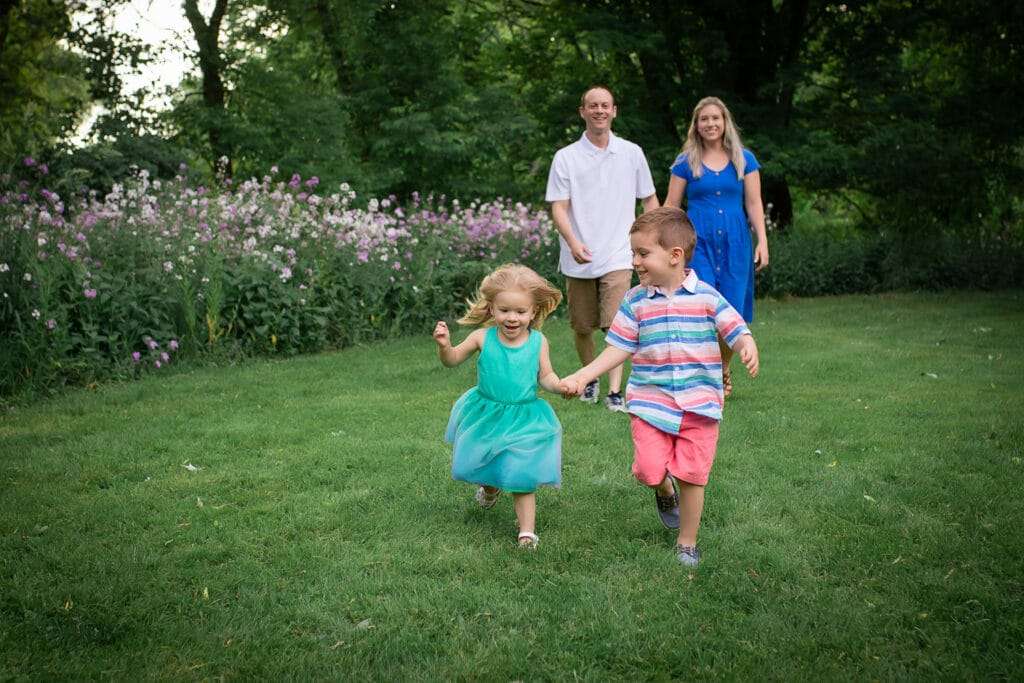 family photographer in rochester ny captures family playing together at sunset in the wildflowers