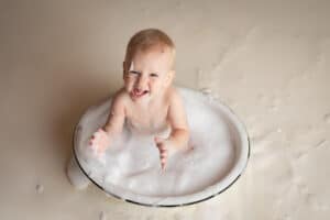 newborn photographer in rochester ny captures baby splashing in a bubble bath