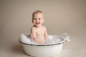 newborn photographer in rochester ny captures baby splashing in a bubble bath