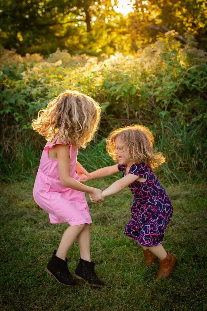 family photographer in rochester ny captures family playing together in a field at sunset