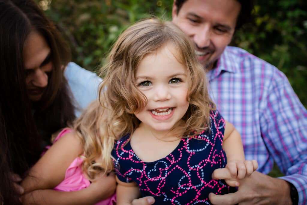 family photographer in rochester ny captures family playing together in a field at sunset