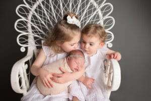 newborn photographer in rochester ny captures sleeping newborn baby with her sisters