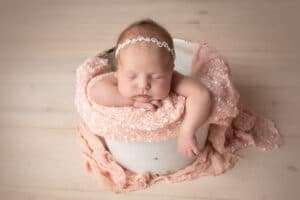 newborn photographer in rochester ny captures sleeping newborn baby in a bucket