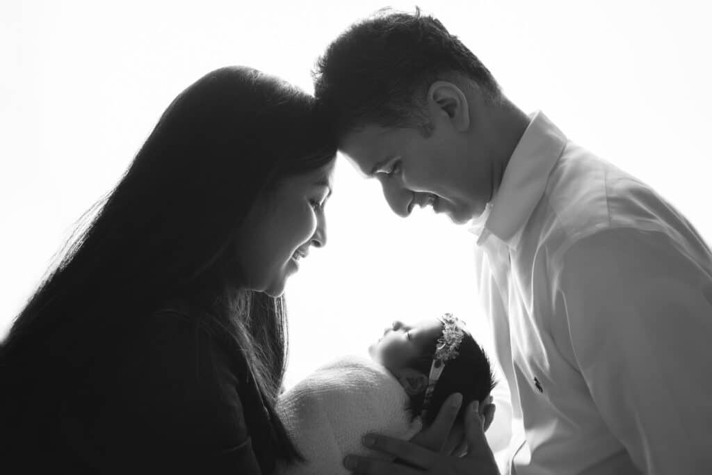 newborn photographer in rochester ny captures baby girl sleeping in her parents' arms