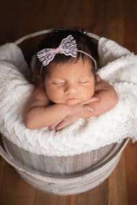 newborn photographer in rochester ny captures baby girl sleeping in a bucket