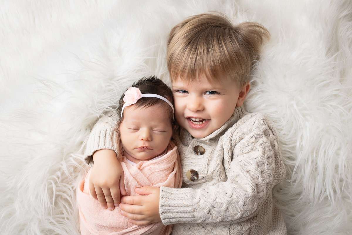 newborn photographer in rochester ny captures big brother holding his newborn baby sister