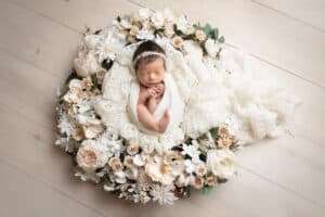 newborn photographer in rochester ny captures newborn baby girl sleeping in a floral wreath