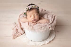 newborn photographer in rochester ny captures newborn baby girl sleeping in a bucket