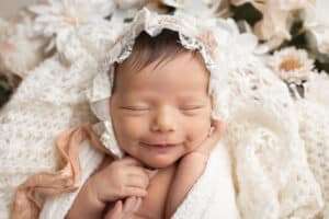 newborn photographer in rochester ny captures newborn baby girl smiling in her sleep