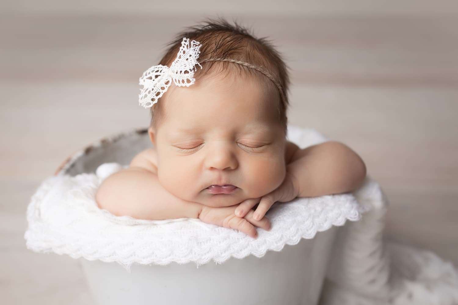 newborn photographer in rochester ny captures newborn baby girl sleeping chin on hands in a bucket