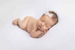 newborn photographer in rochester ny captures newborn baby girl in side lay pose