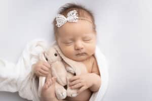 newborn photographer in rochester ny captures newborn baby girl sleeping with a stuffed bunny
