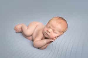 newborn photographer in rochester ny captures newborn baby boy sleeping in side lay pose