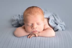newborn photographer in rochester ny captures newborn baby boy sleeping chin on hands