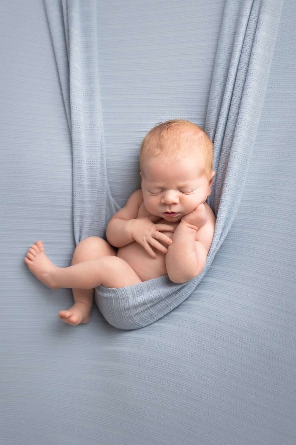 newborn photographer in rochester ny captures newborn baby boy sleeping in hammock pose