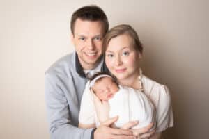 newborn photographer in rochester ny captures newborn baby girl sleeping in mom and dad's arms