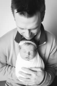 newborn photographer in rochester ny captures newborn baby girl sleeping in dad's arms