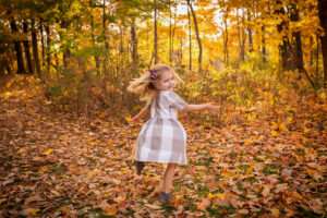family photographer in rochester ny captures family playing in the fall leaves in fall mini session