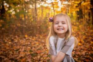 family photographer in rochester ny captures family playing in the fall leaves in fall mini session