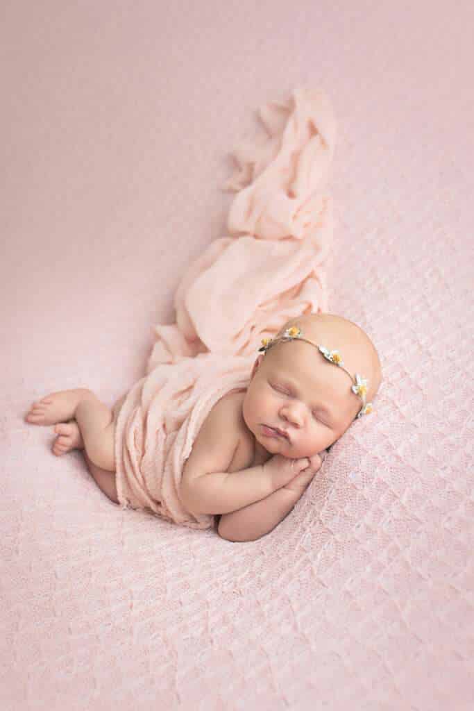 newborn photographer in rochester ny captures newborn baby girl in side lay pose