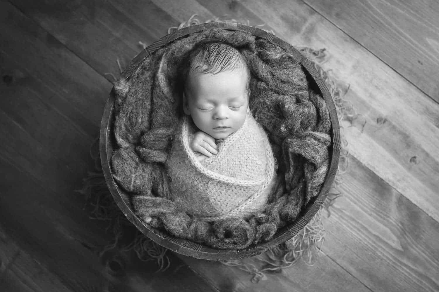 newborn photographer in rochester ny captures newborn baby boy asleep in a bucket