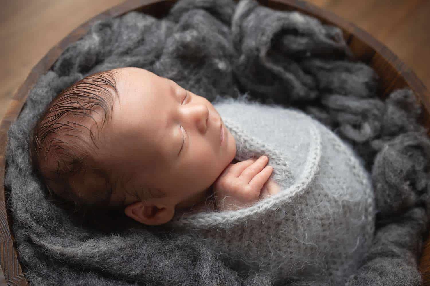 newborn photographer in rochester ny captures newborn baby boy asleep in a bucket